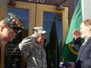 Army Sgt. 1st Class David Sivewright, center, presents the flag he carried more than 2,000 miles to Ridgefield City Councilman Darren Wertz, right, on the steps of Ridgefield City Hall.