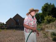 Julia Spellman, 87, hoses down thistle in a bioswale by her home near Prairie High School recently.