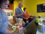 Natalie Shumaker, 4, tastes a gummy worm while her mother, Katy Shumaker, holds her cup of frozen yogurt and grandparents Tom and Liz Shumaker pay in the background at Yo 2 Go frozen yogurt shop Wednesday in Vancouver.