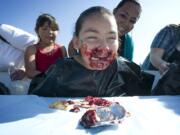 Jayleene Arellano, 10, of Vancouver, competes in a pie-eating contest Saturday at the Harvest Fun Day at Heritage Farm in Hazel Dell. Her mother, Olivia Arellano, and sister Aaliyah, 8, cheer her on.