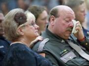 Lewis County Sheriff's Sgt. Ross McDowell is comforted by his wife, Rita, after speaking Saturday at a memorial service at Woodland High School for La Center Police Officer Scott Reinecke. Reinecke died Sept. 10 at the age of 51 from an unknown medical issue. McDowell was among between 150 to 200 people who turned out to pay tribute to Reinecke, a 13-year veteran officer of the department. McDowell knew Reinecke for almost 30 years after being cadets together at police academy in St.