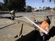 Kirk Wallen, right, and Marcos Valencia of C2 Utility Contractors install four-inch conduit for fiber optic cables at the intersection of Main Street and Mill Plain Wednesday in Vancouver.