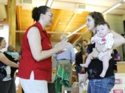 Desiree de Monye, left, talks with her daughter Emily de Monye -- who holds her own 3-month-old daughter, Charlotte de Monye -- as they tour the Oliva Family Early Learning Center after Thursday's dedication at Clark College.