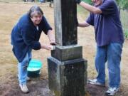 Doris Bishop and Jim Williams from The Church of Jesus Christ of Latter-day Saints Fairway Village Ward scrub a cemetery monument at the Fisher Cemetery during the church's Day of Service.