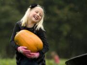 Marissa Maunu, 8, of Battle Ground, lets out a huff as she heaves a pumpkin into a waiting wheelbarrow Sunday at Pomeroy Living History Farm.