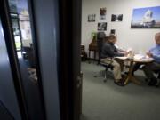 Photographer Tim Stewart, right, discusses his business plan with business adviser Buck Heidrick at the offices of the Small Business Development Center.