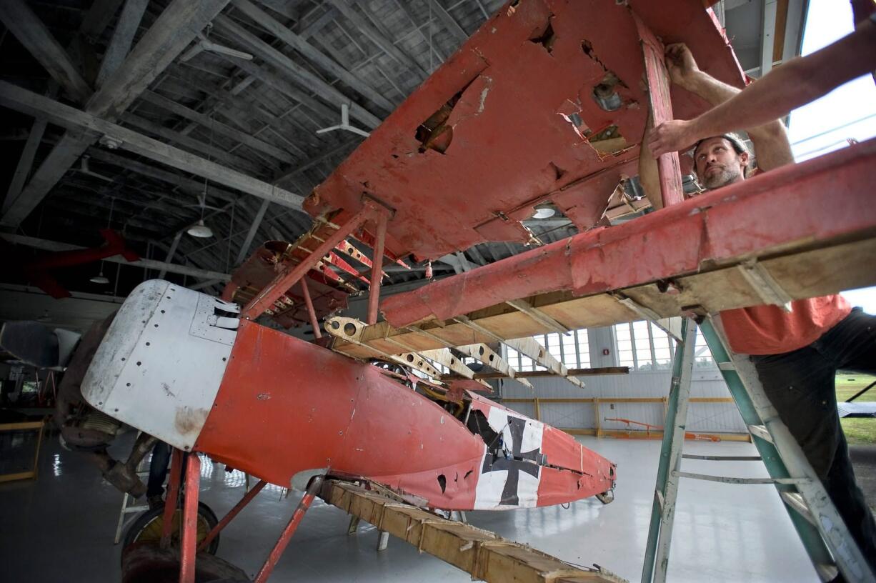 Patrick Garrison, right, fastens the top wing of his replica Fokker Dr.1 triplane Friday at Pearson Air Museum.