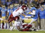 UCLA wide receiver Josh Smith, right, is tackled by Washington State safety Jordan Simone (19) and safety Anthony Carpenter (4) during the first half Saturday.