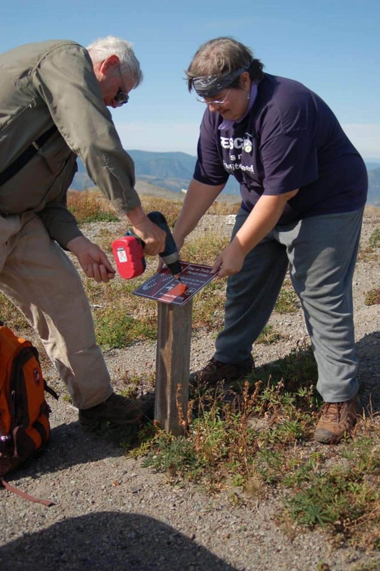 Jerry Whittig, left, of Edgewood and Anthea Fallen-Bailey of Vancouver install resource protection signs near Johnston Ridge Observatory during the 2011 National Public Lands Day.