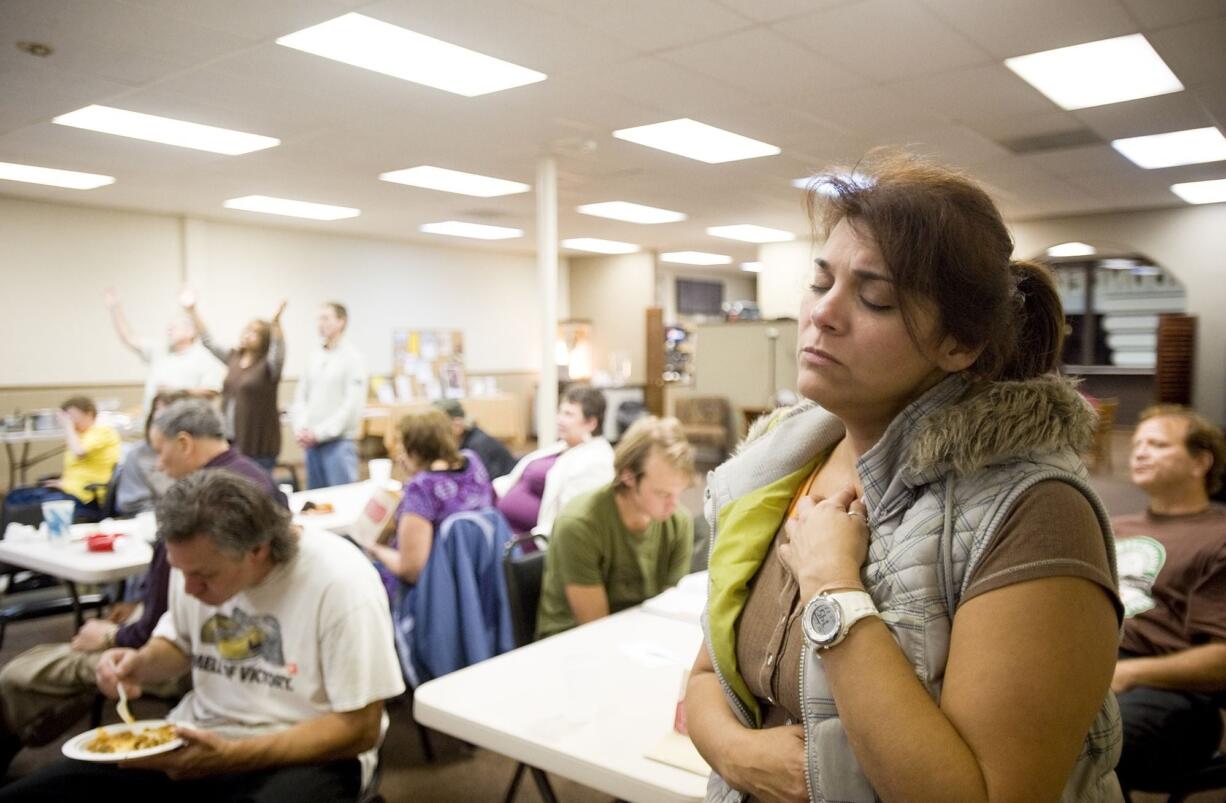 Analisa Clymer of Vancouver closes her eyes in prayer during singles night activities Thursday at the Clark County Christian Center in Vancouver. Top: Annette North, center, had a vision to start Clark County Christian Center 12 years ago after enduring a divorce and the death of her father. The center formally opened Sept.