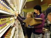 New Seasons employees Janet Christenson, from left, Chelsea Haskell and Keith Haskell stock shelves ahead of the Fisher's Landing store's Nov.