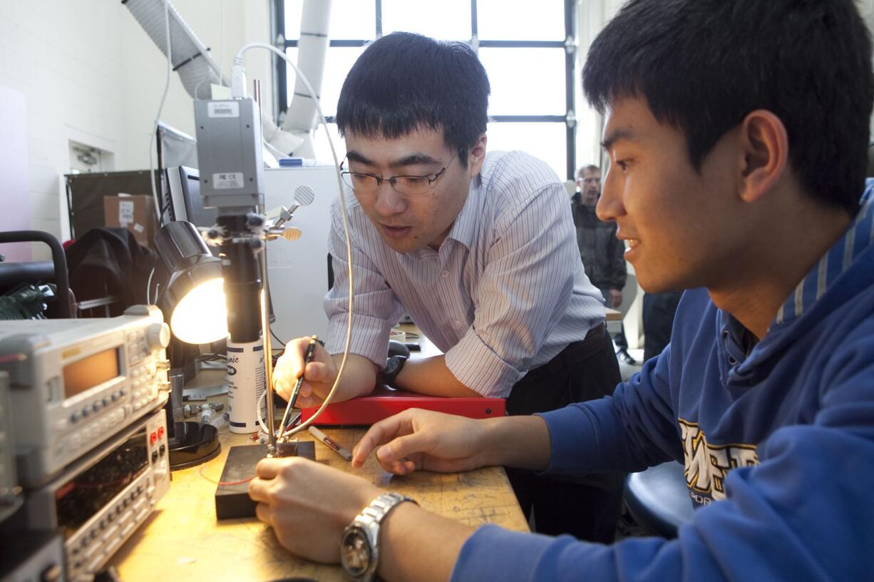 Washington State University Vancouver assistant professor Jie Xu, left, works with grad student Mike Yu.