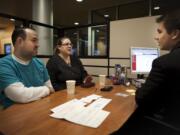 Dan Boggs, member service officer at iQ Credit Union, helps Liz and Jesse Weiss open a checking account. The couple previously banked at Bank of America but were fed up with fees.