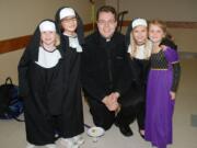 The Rev. Matthew Oakland visits with the mini-saints of Pacific Crest Academy. From left are: Campbell Deringer as St. Rose of Lima; Jane Brotherton at St. Jane; Hannah Jo Hammerstrom as St. Clare; and Anna Mooney as St.