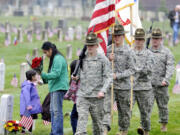 Family members leave flowers at the grave of George Titus as soldiers from the 2nd Brigade, 95th Division, rehearse posting the colors prior to Friday's Veterans Day observance at the Vancouver Barracks Post Cemetery.