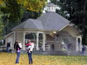 Park visitors watch Saturday as volunteers spruce up the bandstand at Esther Short Park.