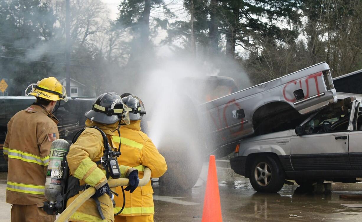 Fern Prairie: Citizen Academy participants Martha Martin and Sheila Plato work with East County Fire &amp; Rescue intern firefighter/EMT Reece Bonenfant to extinguish a fire in the cab of a truck during a Citizens Academy.