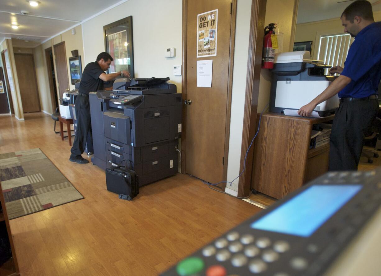 Service technicians for Southwest Office Systems Mariano Lopez, left, and Mitch Shepherd do office work.