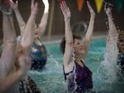 Cathy Harper, center, leaps out of the water during an aqua Zumba class at the Touchmark Health and Fitness Club in east Vancouver.