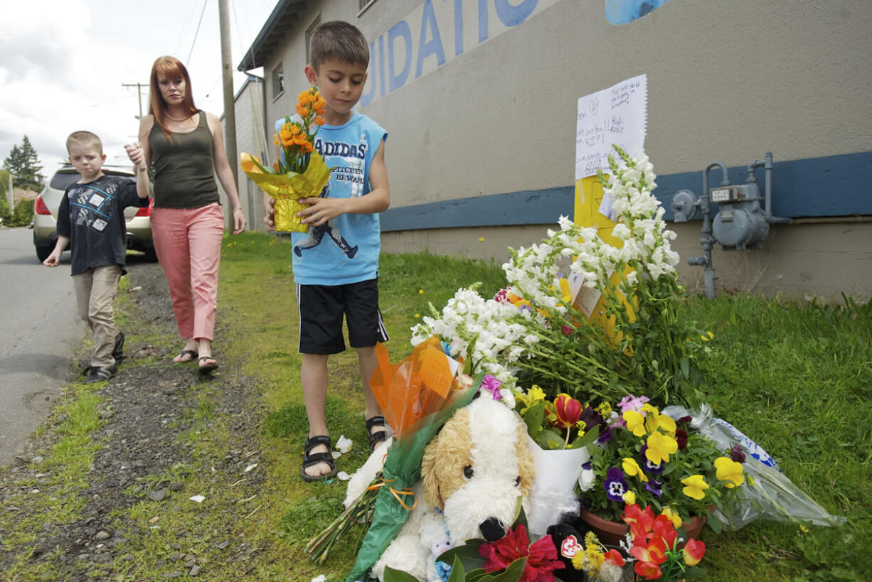 Titus Martin, 7, right, with his mom Mandie Martin and brother Parker Martin, 9, deliver flowers to a memorial for Benjamin Fulwiler at the intersection of Main and 27th streets on Sunday.