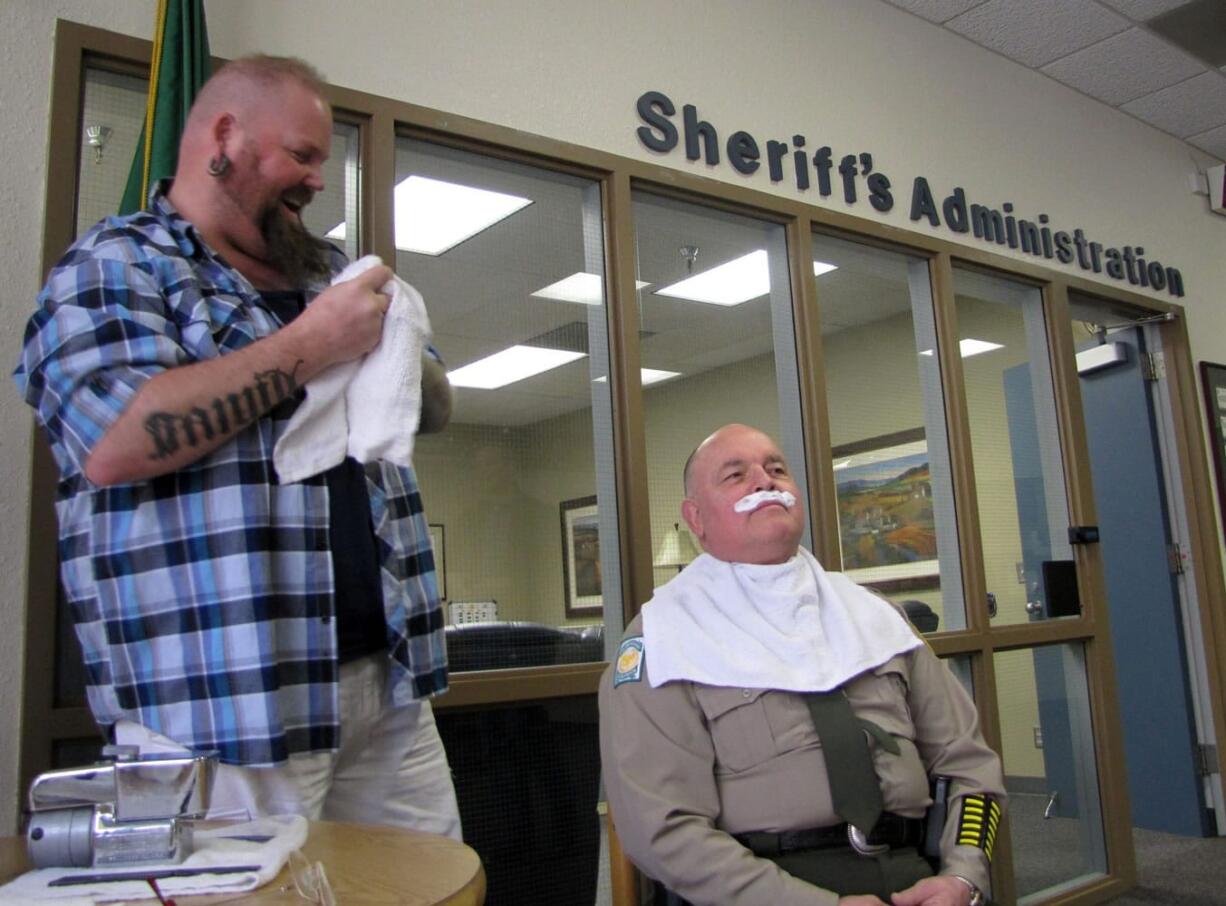 Rick Conn from Bernie and Rollie's Barber Shop, left, prepares to shave Clark County Sheriff Garry Lucas at the sheriff's office headquarters Monday for the annual Moustache March fundraiser for the American Cancer Society.