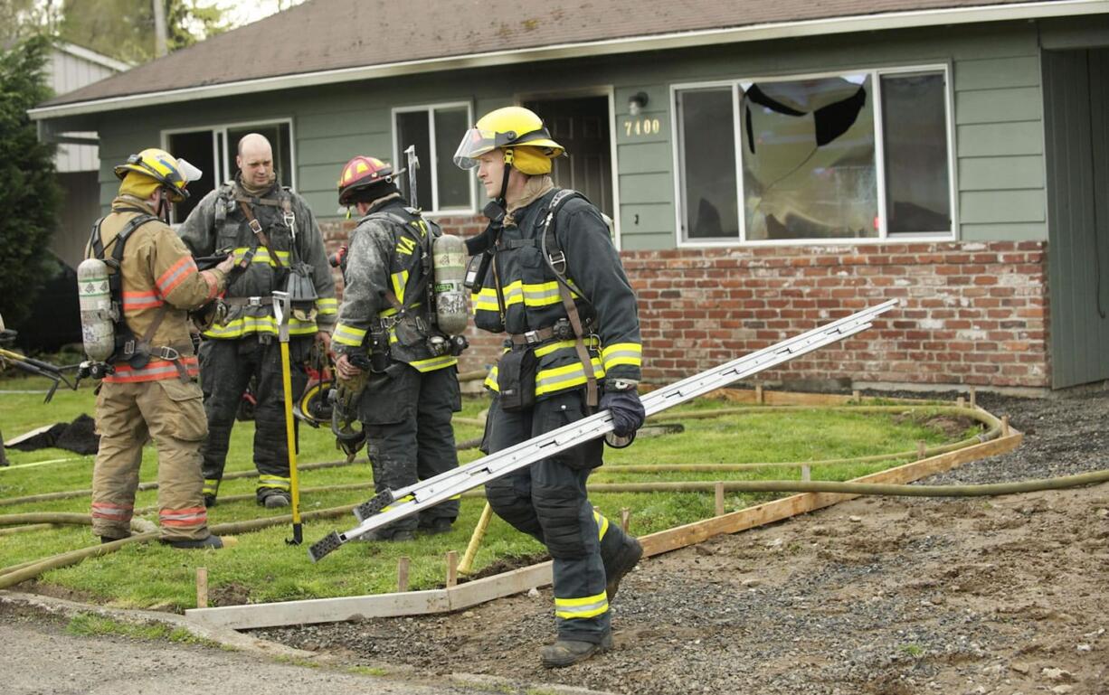 Firefighters from Fire District 6 and the Vancouver Fire Department mop up after fire damaged a rental home at 7400 NW 1st Ave.