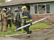 Firefighters from Fire District 6 and the Vancouver Fire Department mop up after fire damaged a rental home at 7400 NW 1st Ave.