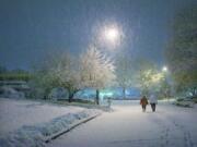 A winter snowstorm inspires Northwest neighborhood residents to take an early-morning walk Wednesday in Vancouver.