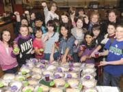 Teacher Erin Lark, top center, and her class show off their freshly made bread dough and jam Monday at Wy'east Middle School in Vancouver.