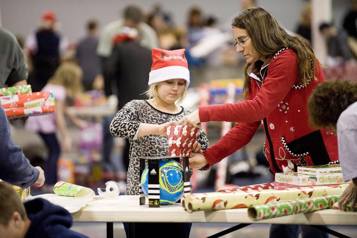 Santa's Posse volunteers Delainey Phelps, 8, and Debbie LaPier wrap presents for needy families Thursday evening.