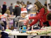 Santa's Posse volunteers Delainey Phelps, 8, and Debbie LaPier wrap presents for needy families Thursday evening.