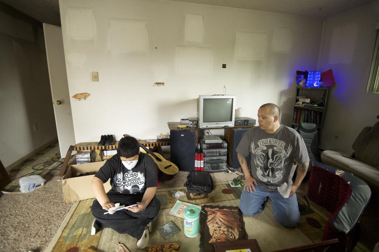 James Smith Jr., 13, left, and James Smith Sr. clean soot-covered personal belongings in their Arnada apartment Thursday morning.