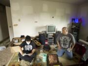 James Smith Jr., 13, left, and James Smith Sr. clean soot-covered personal belongings in their Arnada apartment Thursday morning.