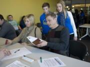 Russian citizens Olga and Andrey Dolbinin, of Vancouver have their information processed before casting their votes in the Russian presidential election on Sunday in the Vancouver Community Library's Klickitat Room. Their children Maksim, 12, and Irina, 15, look on.