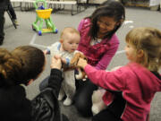 Four-month-old Zylander Studer is the center of attention for Mai Truong, center, Madelyn Ackerman, right, and mom Querida Yerkes, left, during a Second Step parenting class.