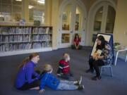 Ondalynn Vance, from left, of Vancouver enjoys Chinese Storytime with her sons, Isaac, 5, and Paxton, 3, as volunteer Amber Huang reads a book at the Camas Public Library. City officials are deciding whether the library should remain independent from the Fort Vancouver Regional Library District.