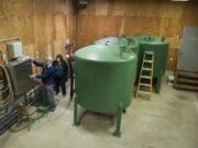 Richard Read, senior environmental scientist for EA Engineering, Science and Technology Inc., left, joins Judy Smith of the Environmental Protection Agency as they check out the ion exchange system that removes hexavalent chromium from water Friday in Hazel Dell.