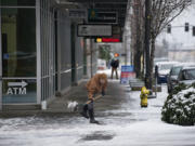 Jerrad Isch of Vancouver shovels ice and snow to clear a pathway to Umpqua Bank for customers in downtown Vancouver on Monday morning.