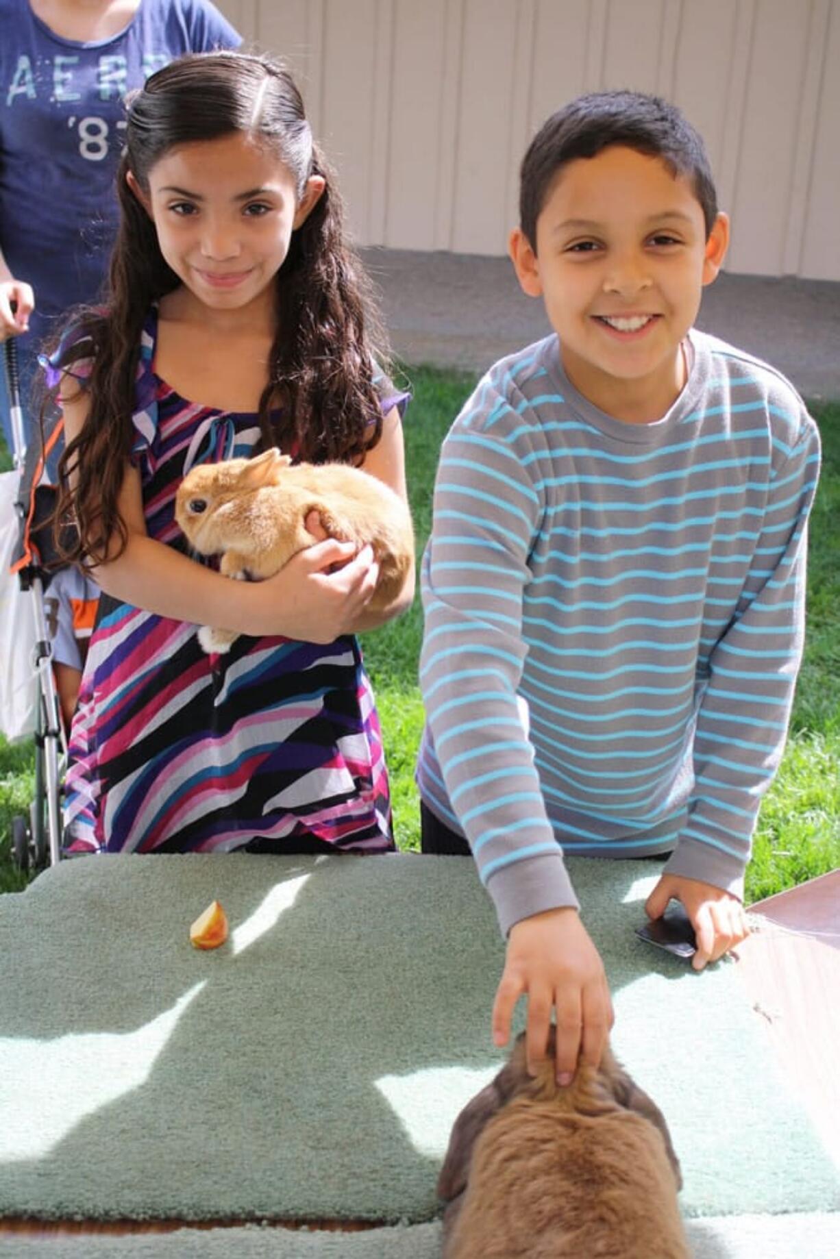 Glenwood: Jissel Valenca, 8, and Anthony Santoyo, 10, enjoy stroking soft, fuzzy bunnies at the Latino Resources Fair on April 15.