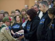 Boy Scout Troop 484 member Scott Brightbill, 13, hands Renee Sherrell, mother of Cody Sherrell, a U.S. flag during a ceremony in Cody's honor Thursday inside the La Center Middle School gym.