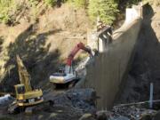 Photos by Steven Lane/The Columbian
The process of removing Condit Dam continued Friday as crews used heavy machinery to chip away at the concrete structure.  Top: Crews use heavy machinery to move sediment built up over a century into the White Salmon River, speeding the flushing process and stabilizing the bank.