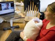 Robbie Mose holds her newborn daughter, Stella, as she talks with her husband, Ryan, via webcam Saturday. Army Staff Sgt.