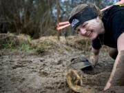 Alissa Fleming, 19, of Vancouver crawls through a final obstacle at the finish of the March Muddy Madness race in Felida on Sunday.