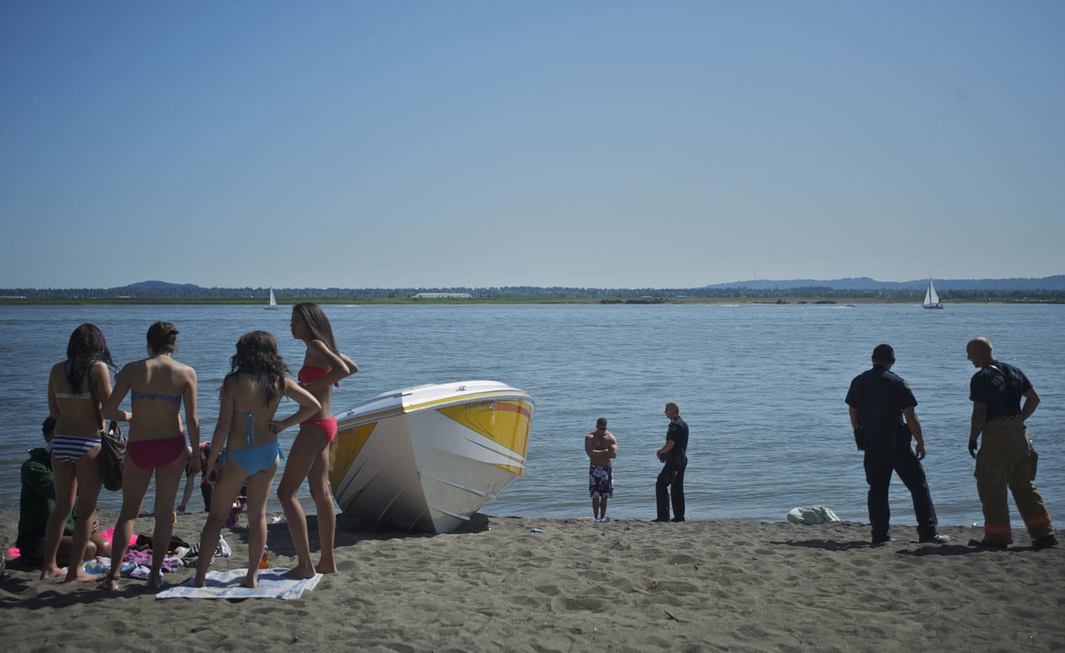 Police investigate a boating accident at Wintler Park on Saturday while people who had gone to the beach to enjoy the warm afternoon watch.