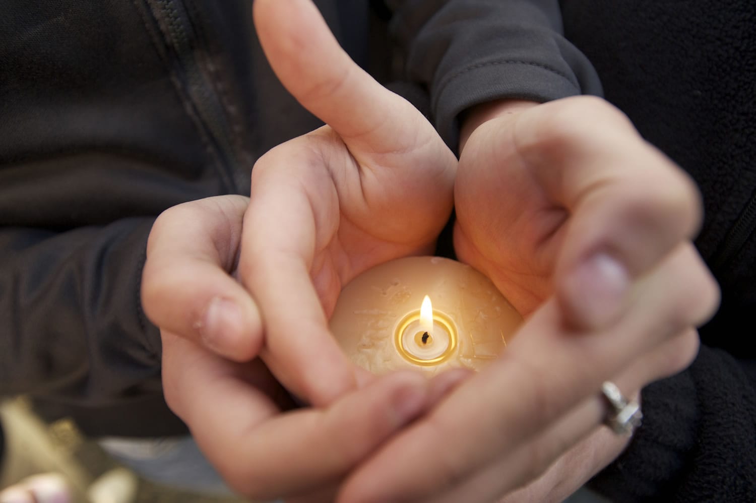 An attendee shields a candle flame in cupped hands Friday night at  a vigil outside Becerra's Plaza in Vancouver for Maria Delos-Carrasco Angulo, 25, who was killed Thursday night nearby.