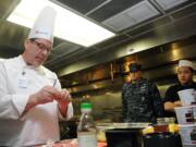 Vancouver: Corporate Executive Chef Greg A. Taylor, from Vancouver, peels garlic while demonstrating food service skills for sailors assigned to the aircraft carrier USS Ronald Reagan in the galley of barge APL-62.