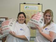 Esther Short: From left, Erin Wright, founder of the Wright Law Firm, and Courtney Claybin, paralegal, hold 50-pound bags of rice that the law firm donated to the Clark County Food Bank.