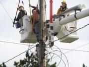 Clark Public Utilities linemen Kenny Cudd, from left, Tommy Jensen and Zach Muonio move conductors as they prepare to replace a power pole in use since 1956.