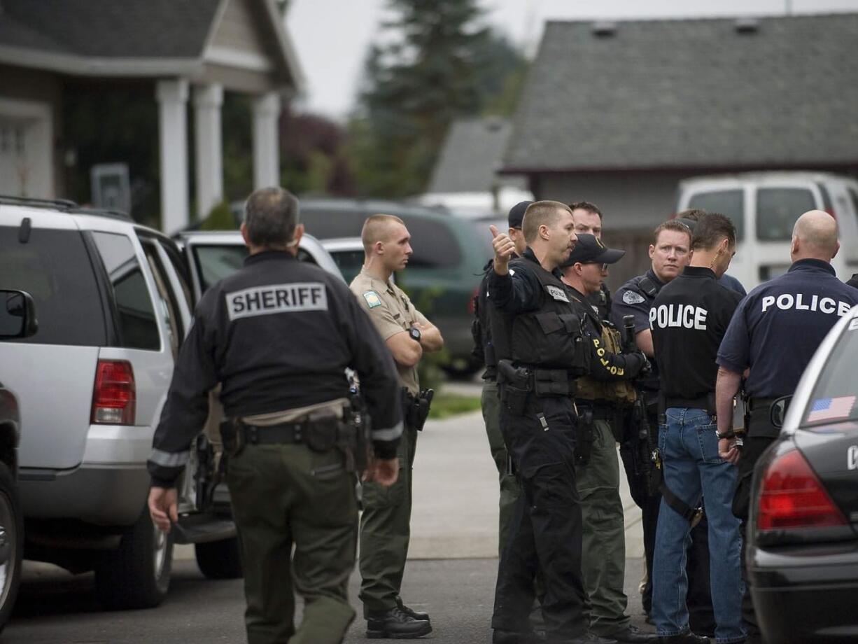 Police officers confer after an early morning drug raid last fall in Vancouver.