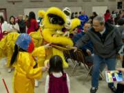 The Lion dancers collects donations as the Vietnamese community of Clark County hosts its New Year Festival in Vancouver.